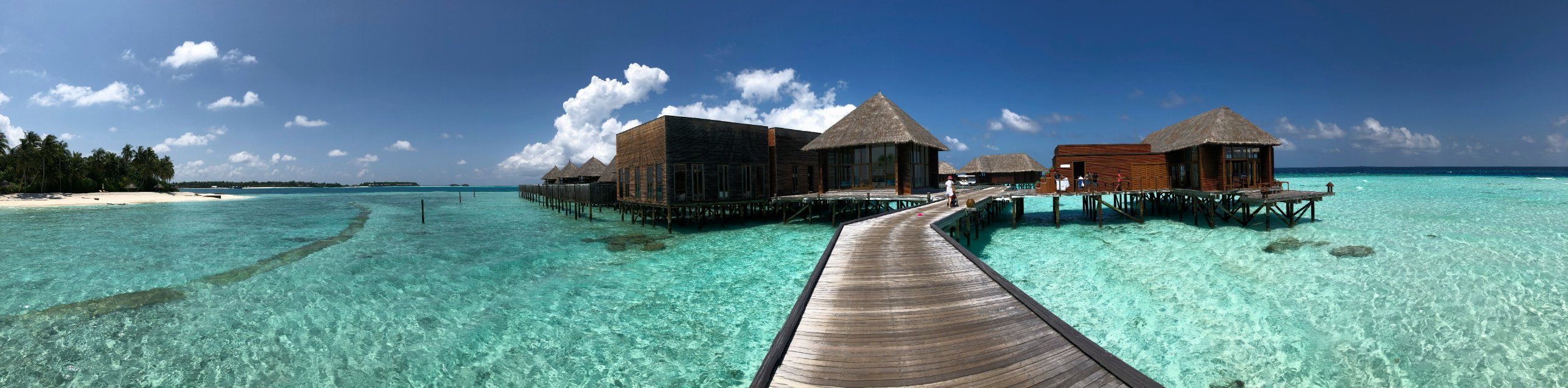 Overwater villas and a wooden boardwalk over turquoise water in the Maldives